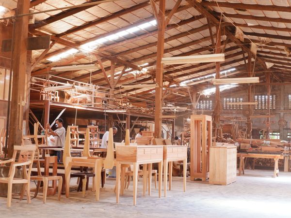 A spacious woodworking shop with furniture and craftsmen working.