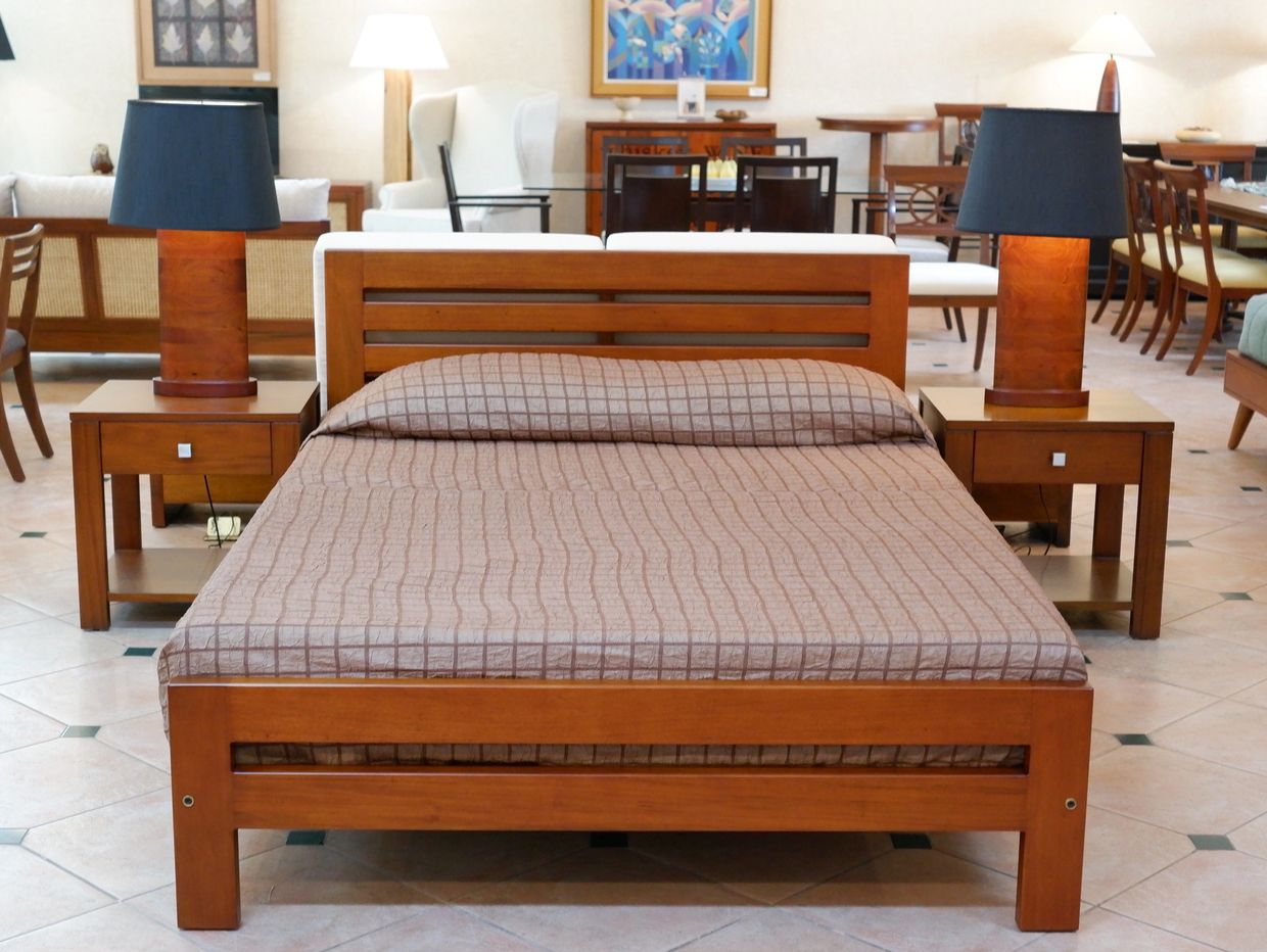 Wooden bed with matching nightstands and lamps in a spacious room.