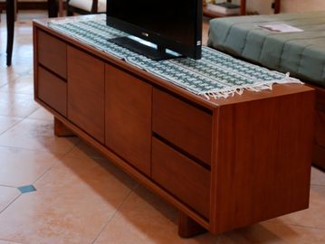 Wooden TV console with drawers and a patterned cloth on top.