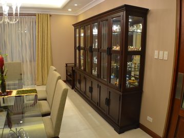 Elegant dining room with glass cabinet and beige chairs.