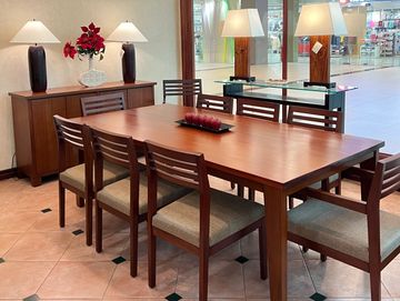 Elegant wooden dining table set with six cushioned chairs in a showroom.