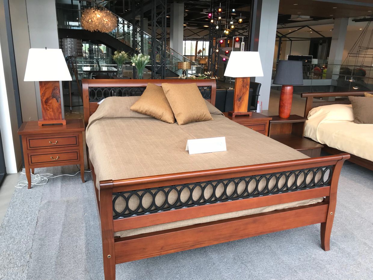 Elegant wooden bed with matching nightstands and lamps in a showroom.