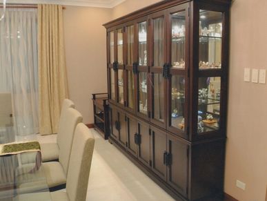 Elegant dining room with a large wooden display cabinet and beige chairs.