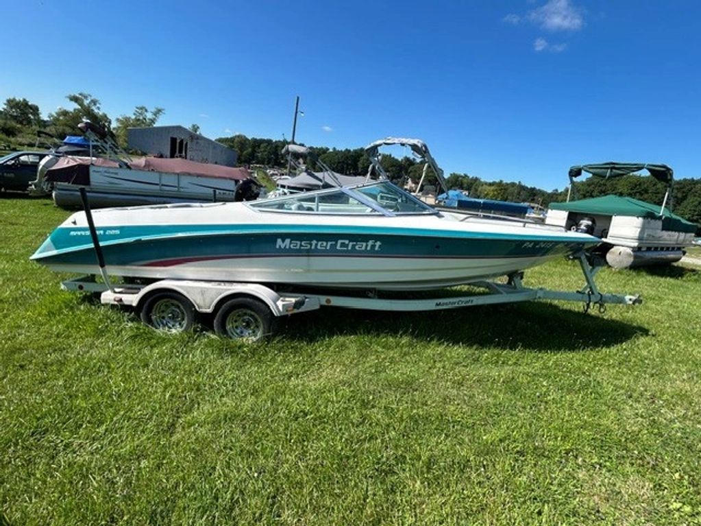 MasterCraft boat on trailer in grassy area.