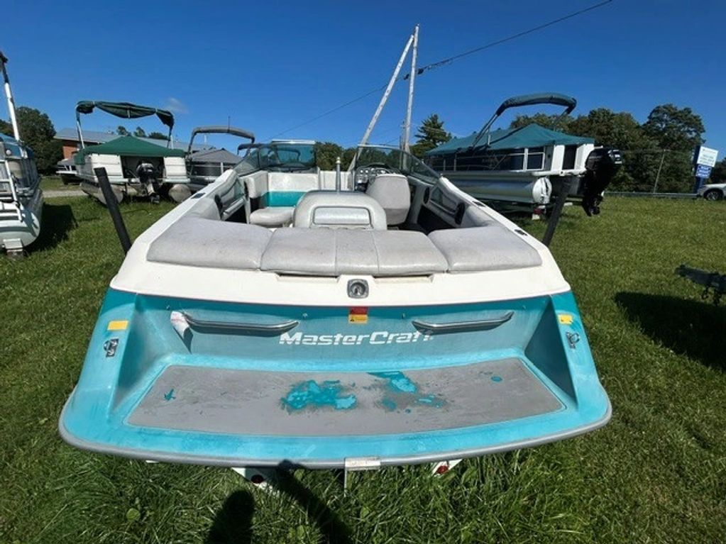 Rear view of a blue and white MasterCraft boat on grass.