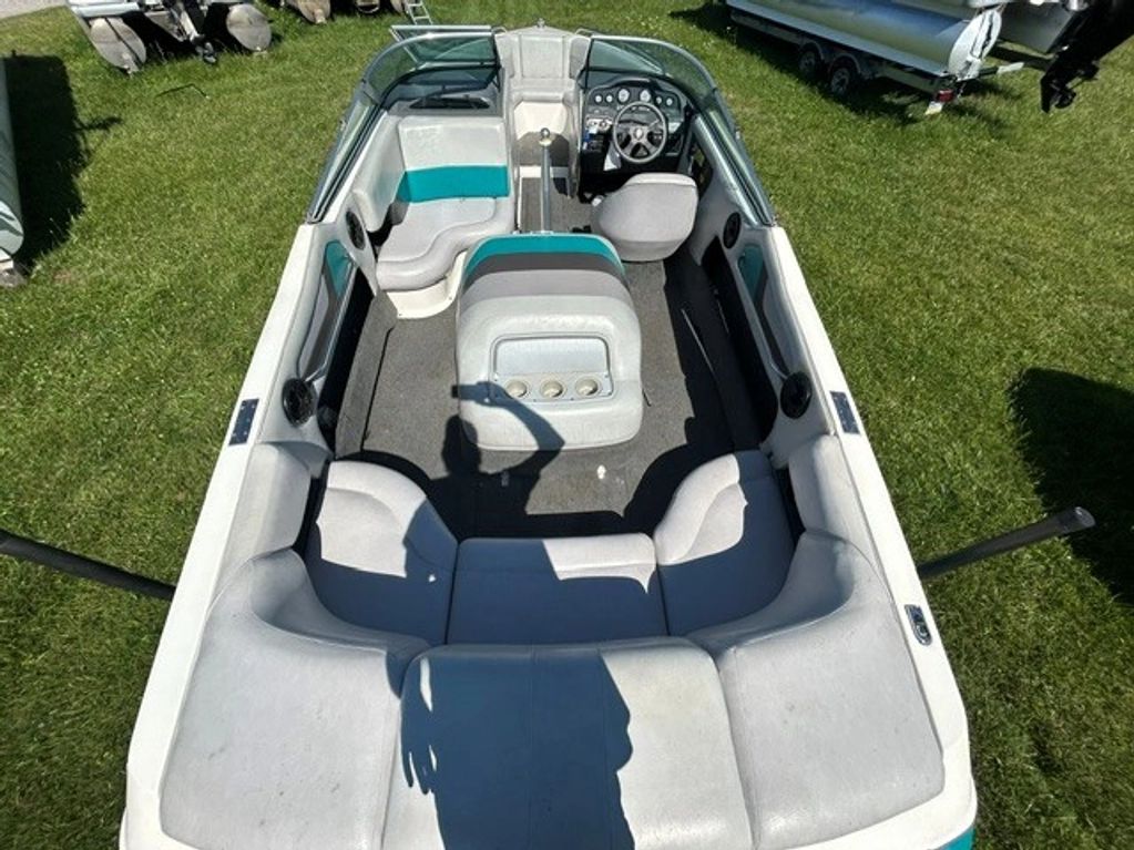 Empty white and teal motorboat interior on grass.