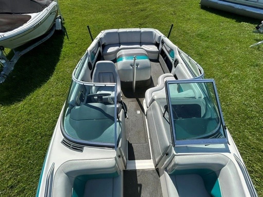 Interior view of a white and teal boat on grass.