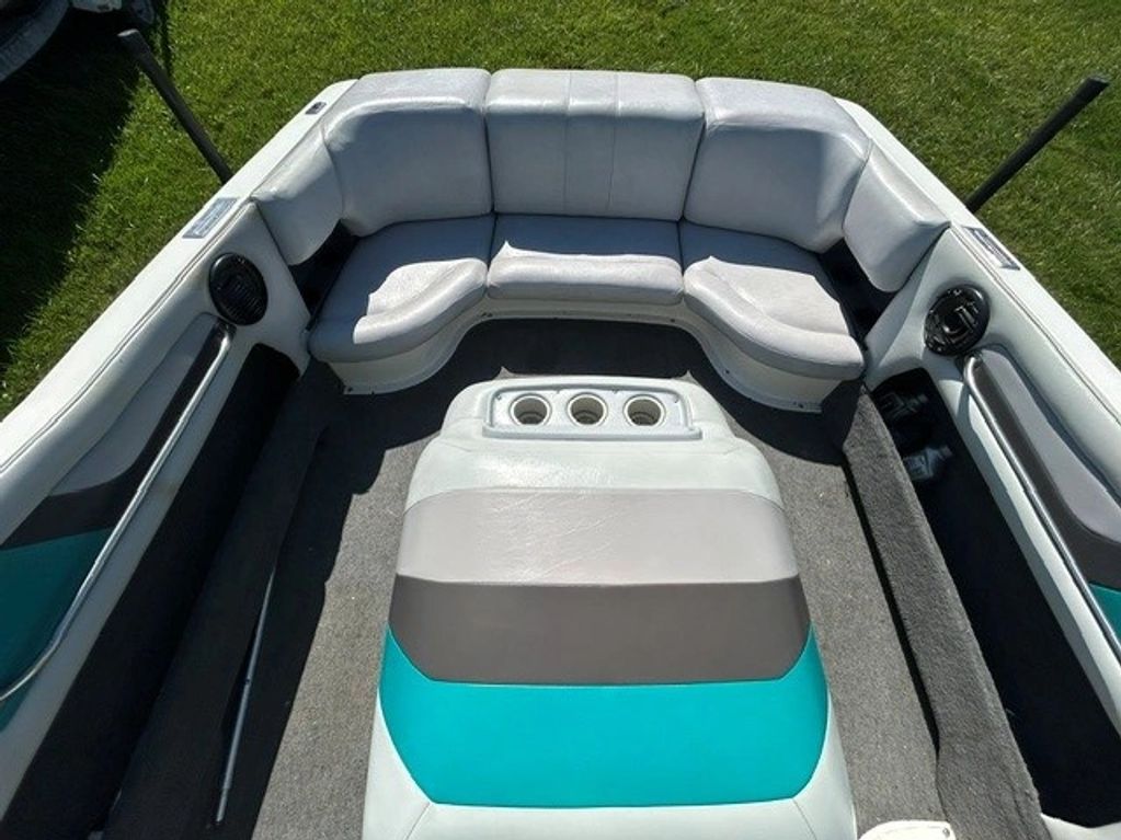 Interior seating area of a boat with gray and teal cushions.
