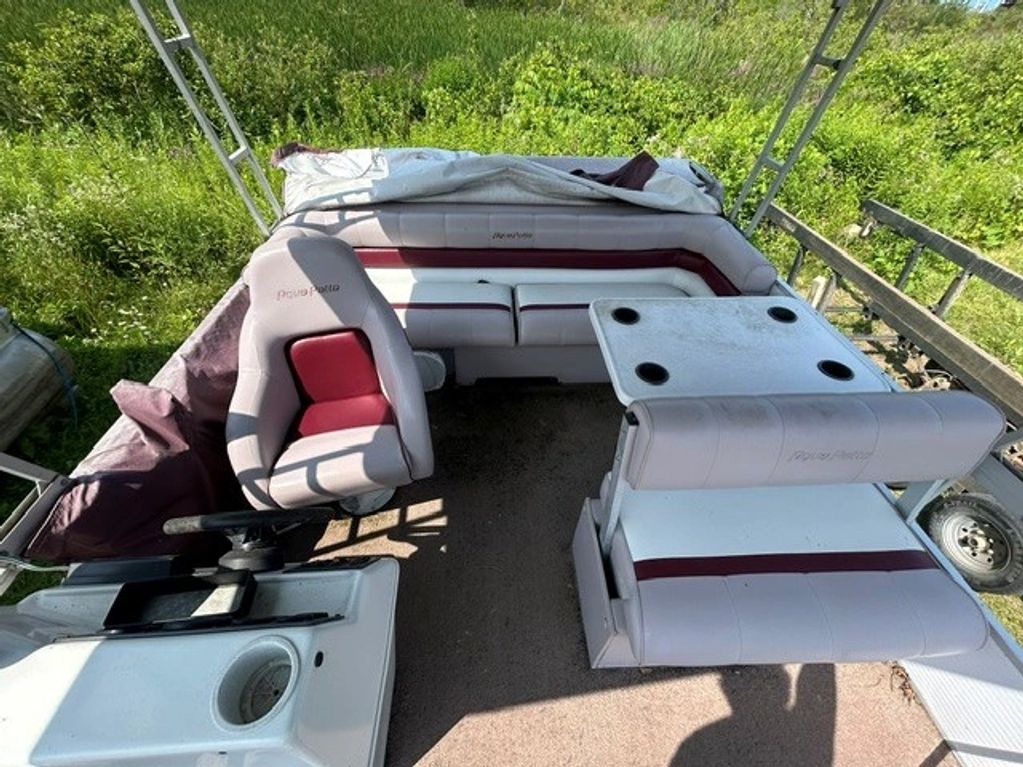 Pontoon boat seating area with driver seat and table.