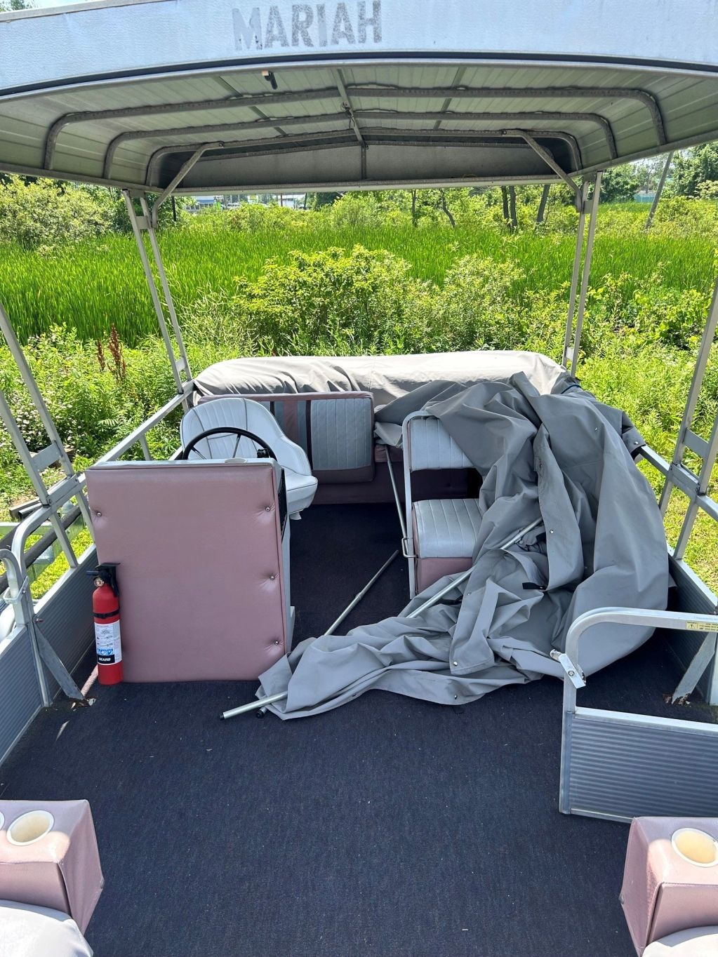 Empty boat named Mariah with scattered seat covers and a fire extinguisher.