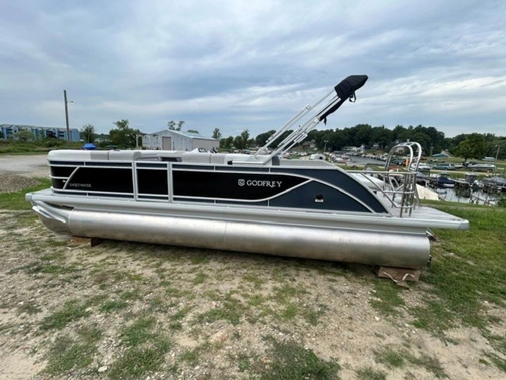 A Godfrey pontoon boat on land near a marina.