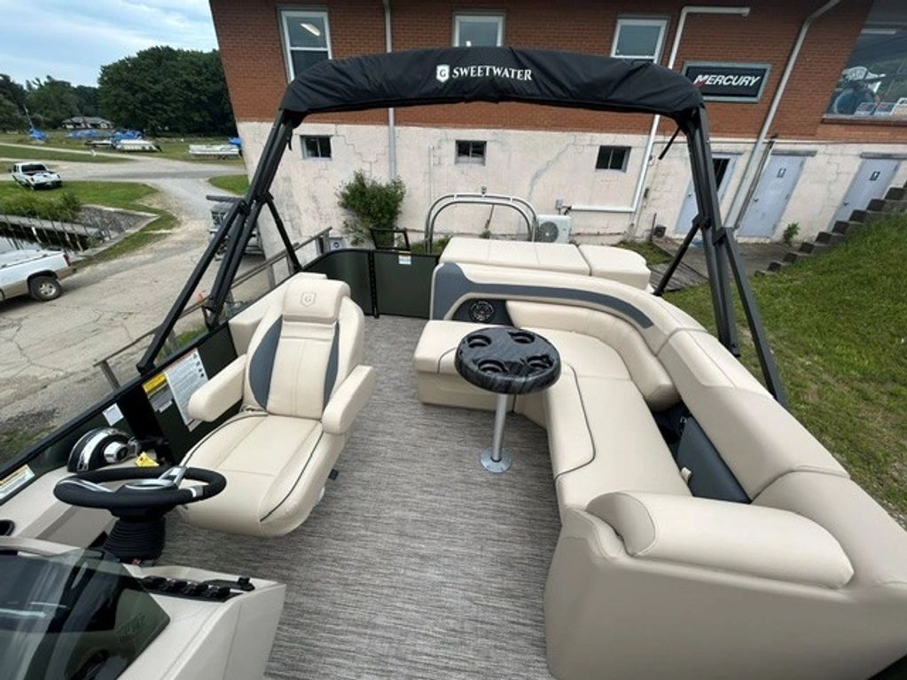 Interior view of a modern pontoon boat with beige seating and a cup holder table.