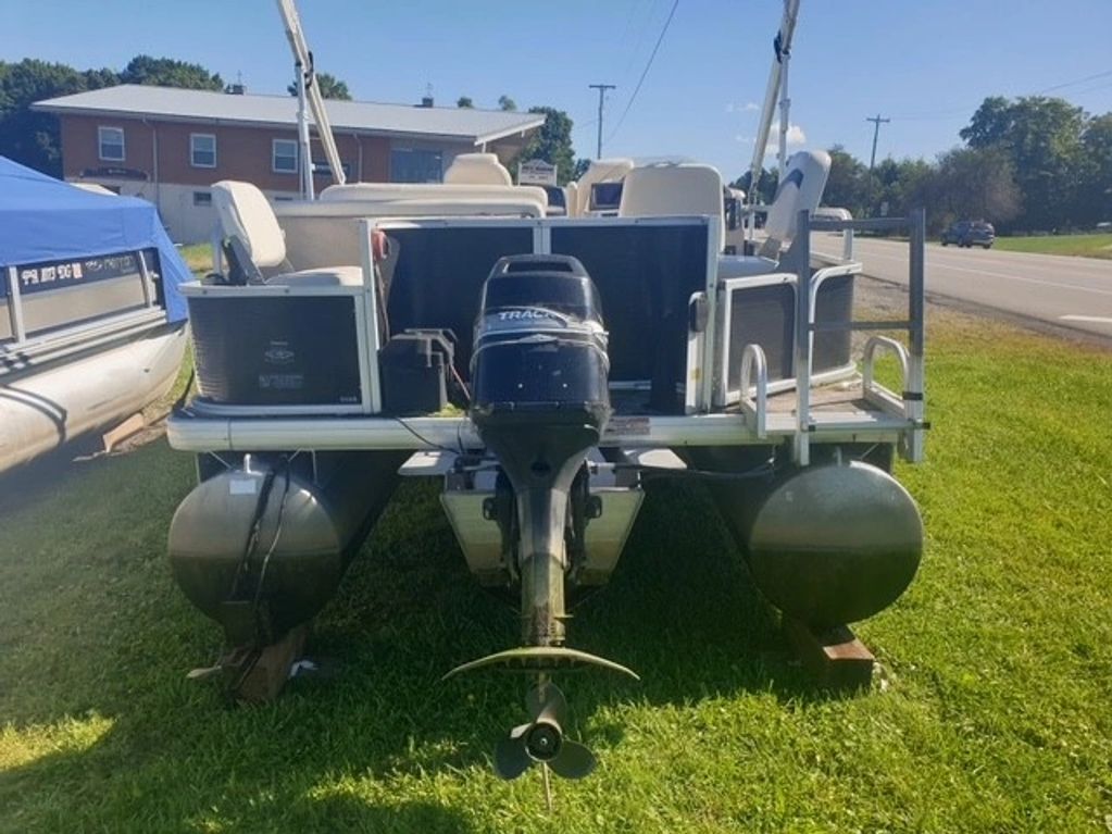 Pontoon boat with motor parked on grass.