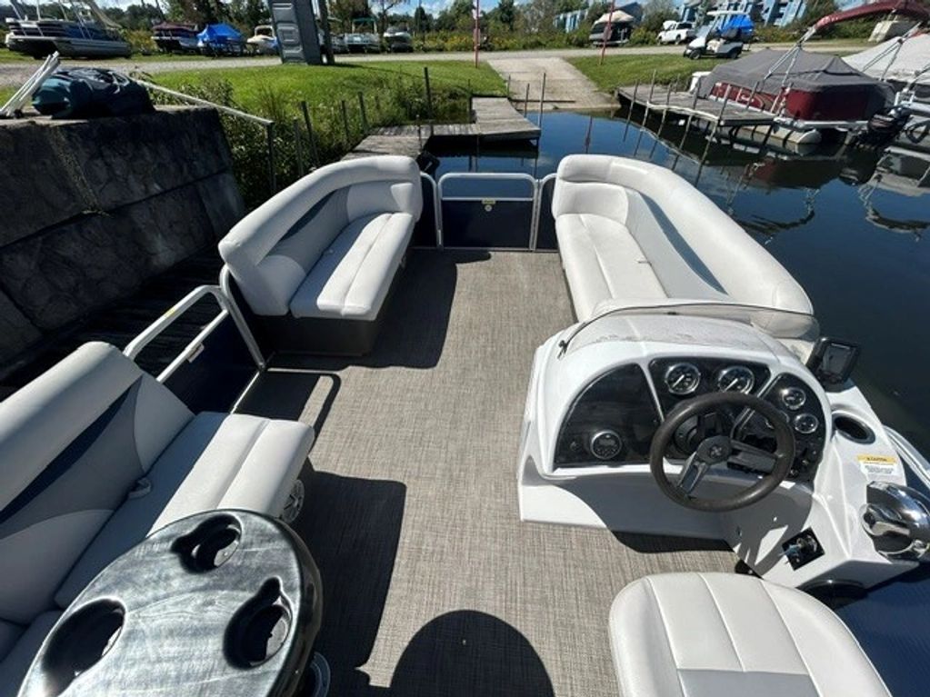 Interior view of a pontoon boat with white seating and steering console.