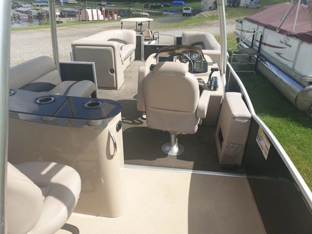 Interior view of a pontoon boat with seats and a steering console.