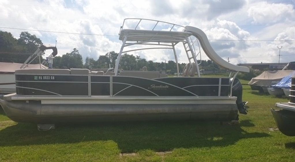 Pontoon boat with water slide on grass.