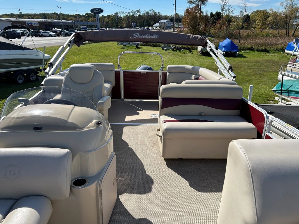 Empty pontoon boat seating area with beige and maroon seats.