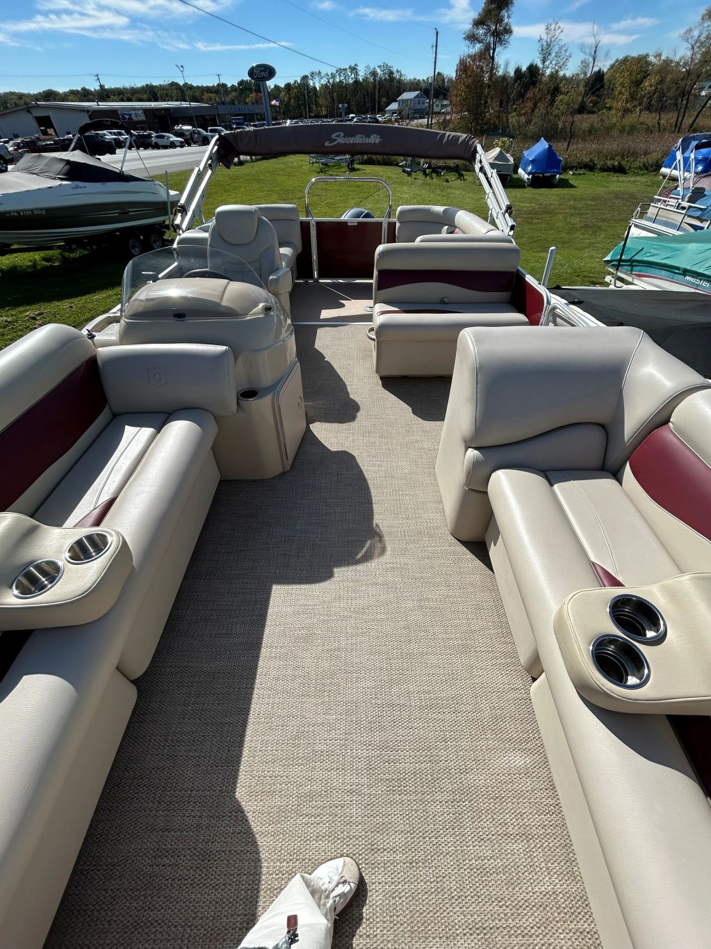 Spacious pontoon boat interior with beige seating and cup holders.