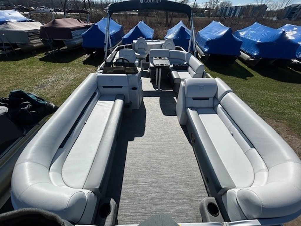 Spacious pontoon boat with plush seating and covered boats in the background.