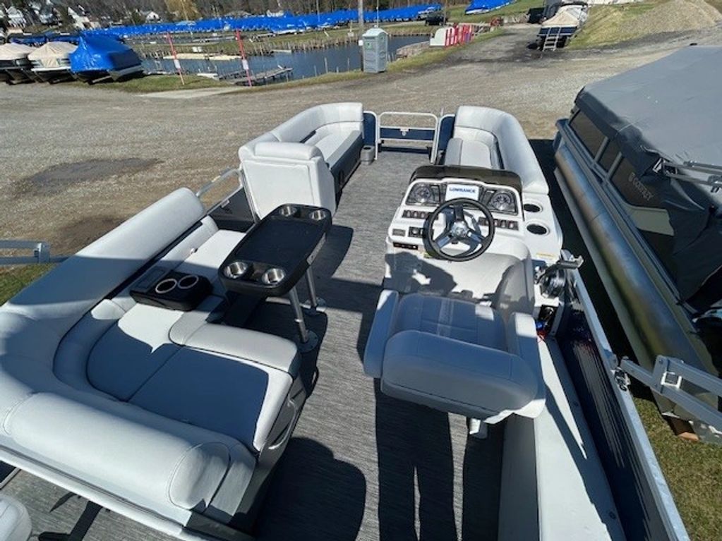 Spacious pontoon boat with white seating and a central steering console.