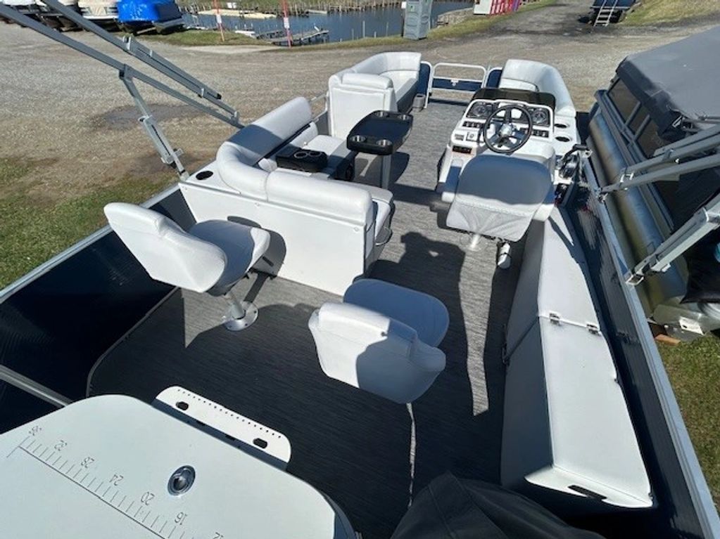 Spacious white seating area on a pontoon boat with a steering console.