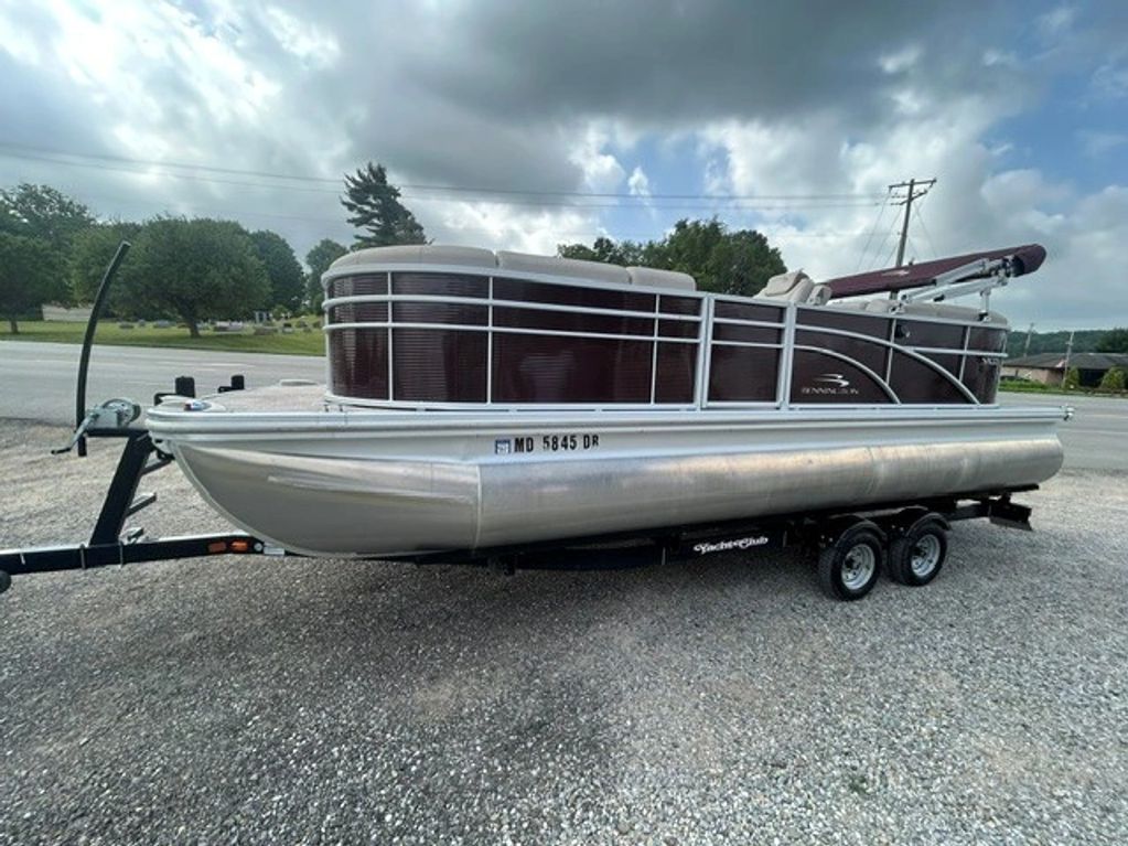 Pontoon boat on a trailer under a cloudy sky.