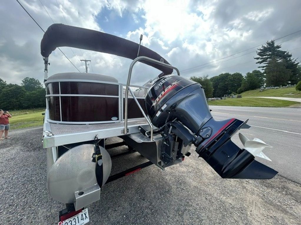 Close-up of a pontoon boat motor on a trailer by the roadside.