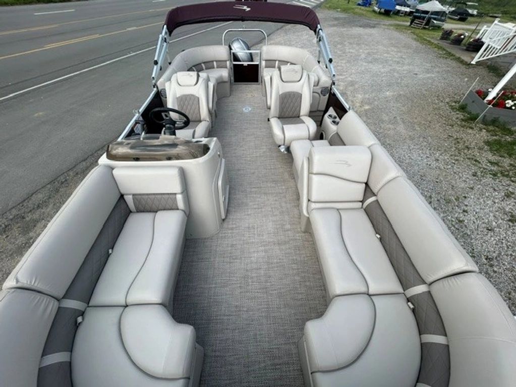 Interior of a beige pontoon boat with spacious seating and a steering console.