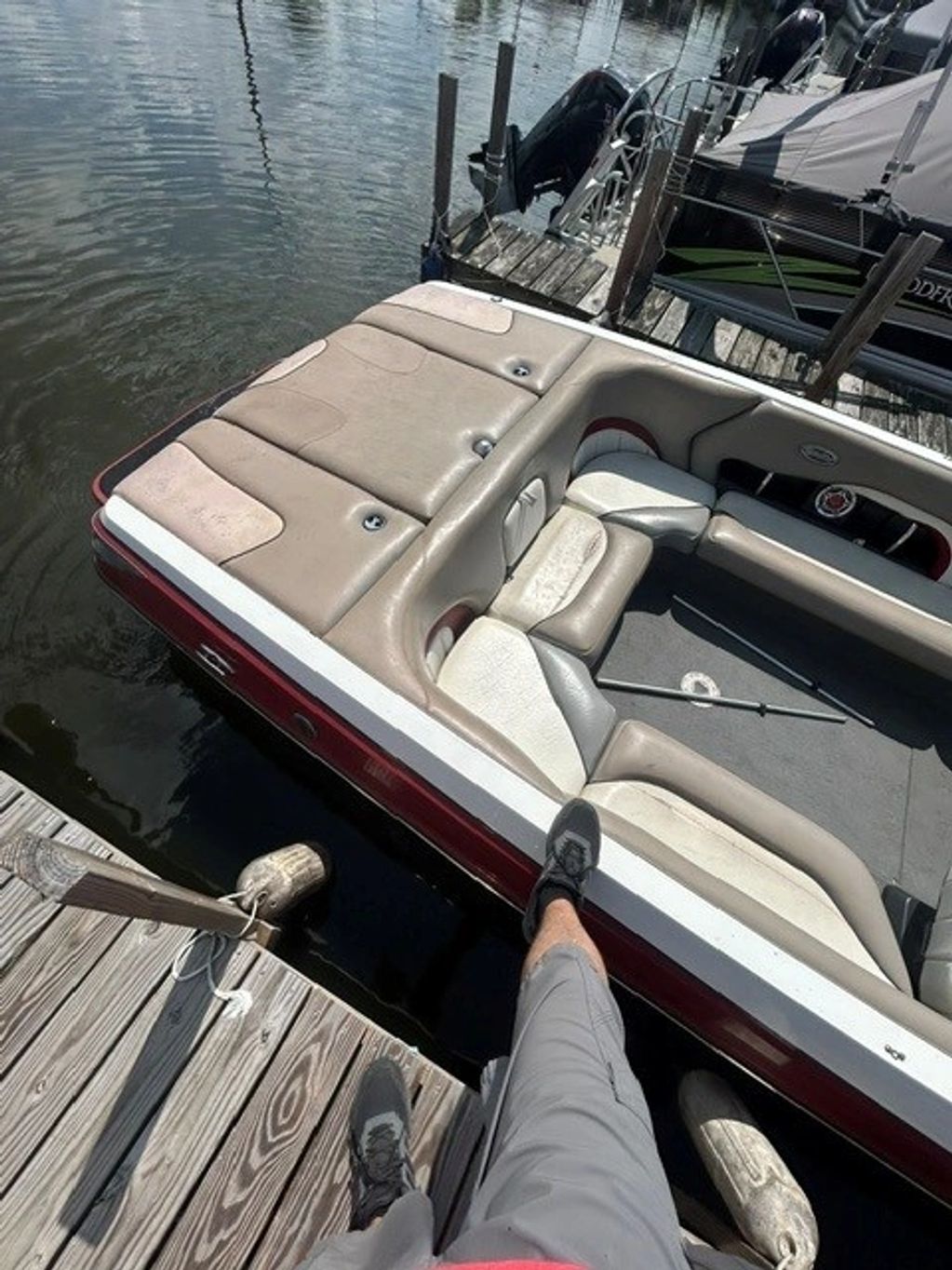 Person stepping from dock onto a boat with beige seating.