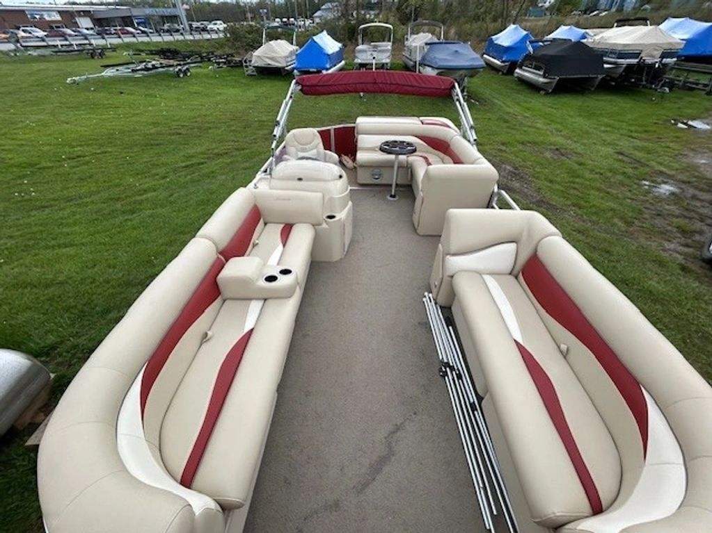Spacious pontoon boat with beige and red cushioned seating.
