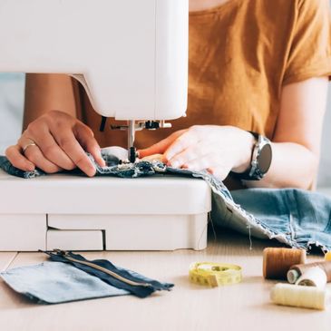 A person sewing blue denim on a white sewing machine