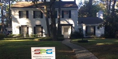 White two-story house with black shutters and a curved walkway.