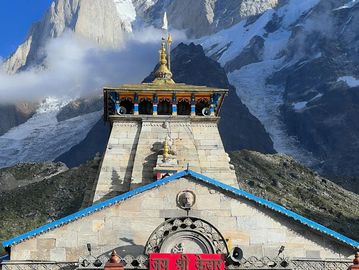 Ancient temple with snowy mountains in the background under a clear blue sky.