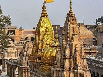 Intricately carved temple spires with golden domes against a clear sky.