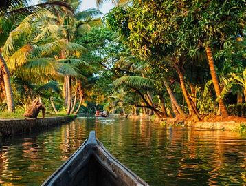 Boat gliding through a serene tropical canal at sunset.