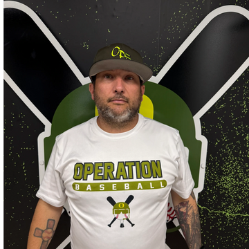 Man wearing an Operation Baseball shirt and cap standing against a sports-themed backdrop.