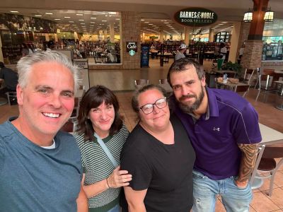 Four friends smiling inside a shopping mall near Barnes &amp; Noble.