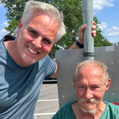 Two men smiling outdoors on a sunny day.