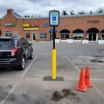 Handicap parking space blocked by a pole with cones nearby.