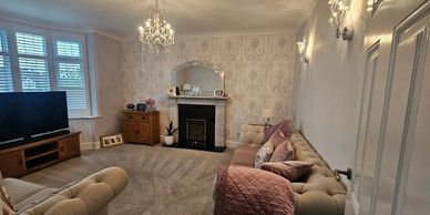 Elegant living room with beige tufted sofas, chandelier, and fireplace.