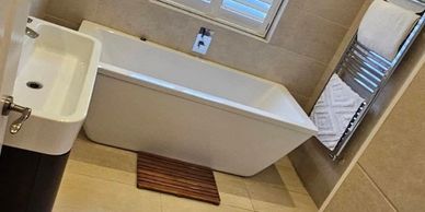 Modern bathroom with a bathtub, sink, and towel rack.