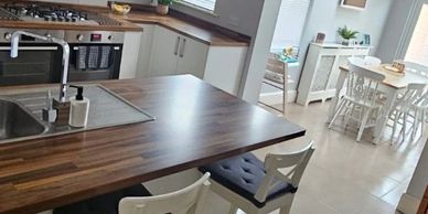 Modern kitchen with wooden countertops and white furniture.