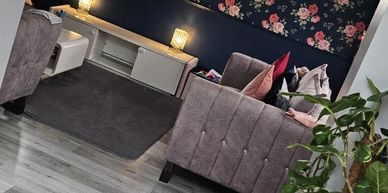 Cozy living room with floral wallpaper, soft couches, and ambient lighting.