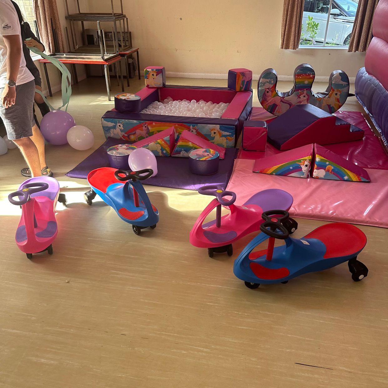 Indoor play area with colorful ride-on toys and a unicorn-themed ball pit.