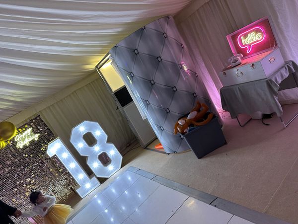 Decorated birthday party setup with light-up number 18 and a photo booth.