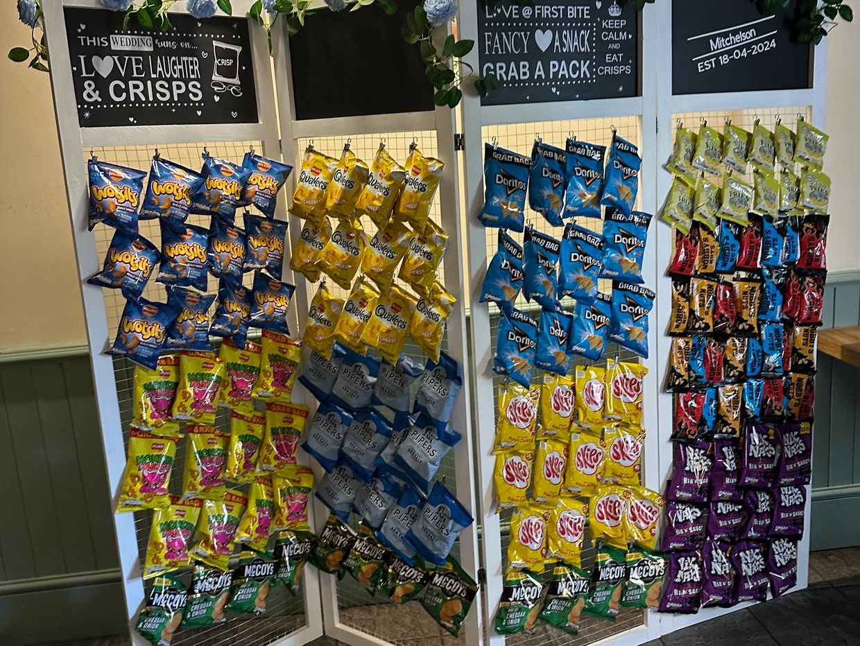 A decorative crisps display with a wedding theme and various snack bags.