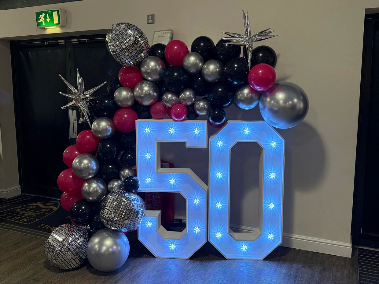 Illuminated number 50 with colorful balloon decoration for a celebration.
