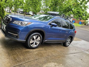 Blue SUV with roof rack on a rainy day.