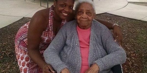 women hugging older woman in wheelchair