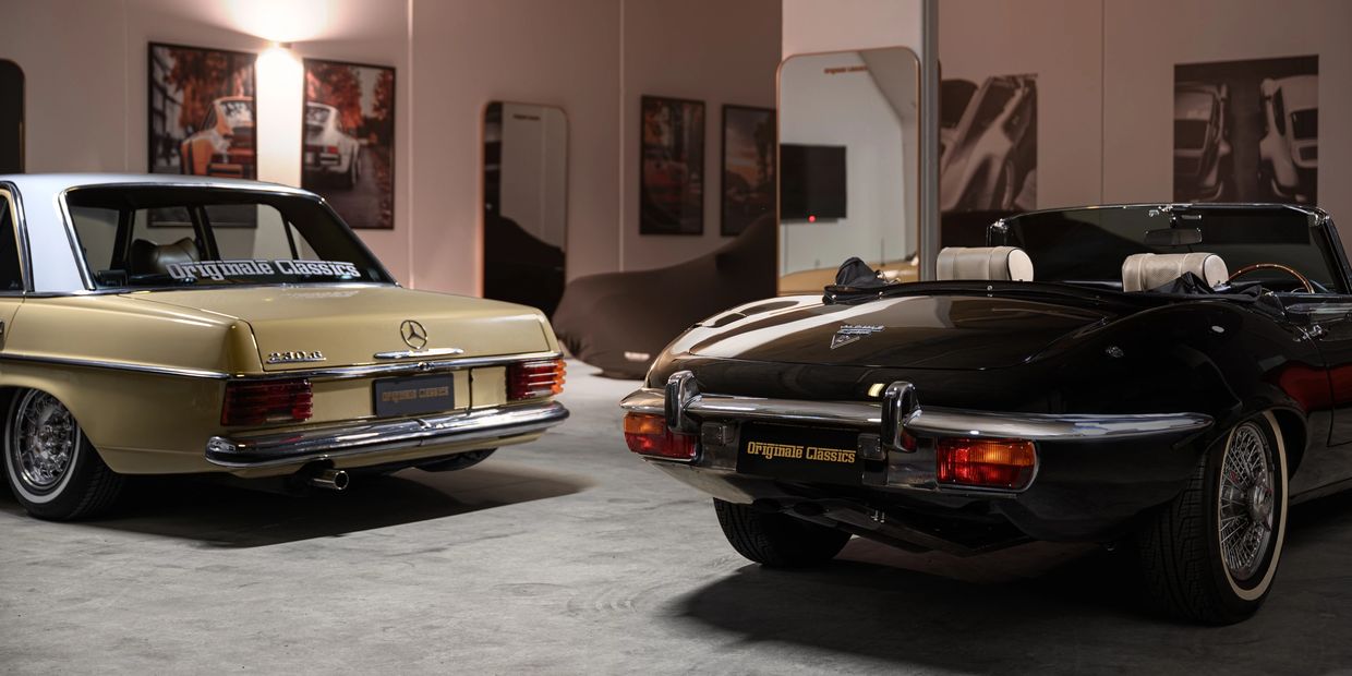 Two classic cars in a showroom with elegant lighting and decor.